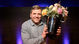 Mann in grauem Hemd mit Blumenstrauss in der linken Hand