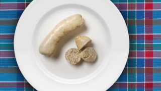 Eine ganze und eine aufgeschnittene Wurst auf einem Teller.