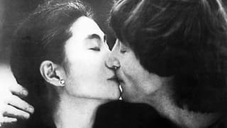 John Lennon und Yoko Ono küssen sich mit geschlossenen Augen.