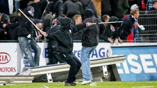 Ein Aarauer Hooligan wirft Fanenstangen gegen die Basler Hooligans nach dem Meisterschaftsspiel 2014.
