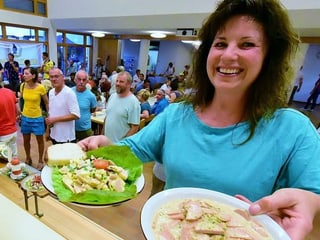 Frau hält Teller mit Wurstsalat.