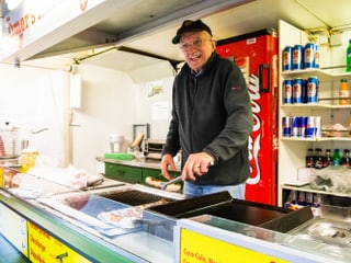 Ömer greift eine Bratwurst mit der Zange. Ömer greift eine Bratwurst mit der Zange.