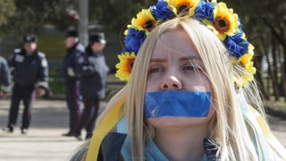 Frau mit ukrainischen Nationalfarben und verklebtem Mund.