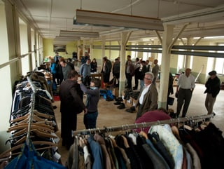 Überblick über Fabrikhalle mit Ständern voll Kleidung, Schuhen, Hüten