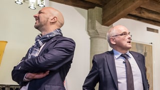 Zwei Männer stehen mit dem Rücken gegeneinander.