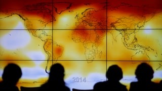 Teilnehmer der Pariser Klimakonferenz vor eine Weltkarte mit aussergewöhnlichen Wetterereignissen