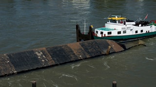 Der Rumpf des Kranschiffes Merlin ragt aus dem Rhein. Daneben ist das Lastschiff Vogel Gryff zu sehen. 