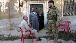 Ein von der Türkei unterstützter syrischer Soldat spricht mit älteren Menschen in Tal Abjad.
