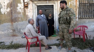 Ein von der Türkei unterstützter syrischer Soldat spricht mit älteren Menschen in Tal Abjad. Ein von der Türkei unterstützter syrischer Soldat spricht mit älteren Menschen in Tal Abjad.