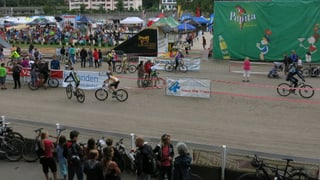 Die Sandbahn des Schänzli mit Bikern, die sich für ihr Rennen einfahren. Im Hintergrund die Zeltstadt mit, rechts ein Teil der Sprungrampe.