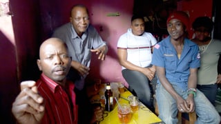 Schwarze Männer beim Biertrinken in einer Bar.