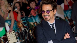Robert Downey Jr. im schwarzen Anzug lächelt in Richtung Fans.