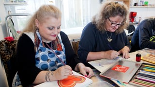 Zwei Frauen sitzen an einem Tisch und malen und zeichnen. Zwei Frauen sitzen an einem Tisch und malen und zeichnen.