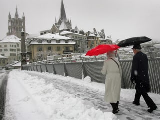 Ein Paar läuft in Lausanne über eine schneebedeckte Brücke.