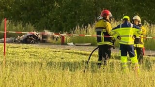 Feuerwehrmänner neben Wrack Feuerwehrmänner neben Wrack