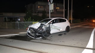 Ein weisses Auto steht mit eingedrücktem Kotflügel beim Bahnübergang kurz vor den Geleisen.