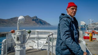 Cousteau steht auf seinem Schiff und starrt in die Ferne.