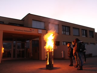 Kinder stehen vor einer brennenden Finnenkerze.