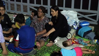 Kinder und Frauen sitzen und liegen auf einer Rasenfläche. Kinder und Frauen sitzen und liegen auf einer Rasenfläche.