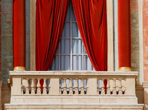 Rote Vorhänge an einem Fenster mit Steinbalustrade.