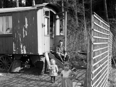Zwei kleine Mädchen mit ihrem Vater vor einem Holzwohnwagen