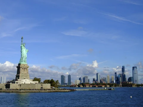 Im Vordergrund ist die Freiheitsstatute in New York, im Hintergrund die Wolkenkratzer von Manhattan.
