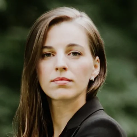 Junge Frau schaut selbstbewusst in die Kamera- Braune Haare, Ohrenschmuck.