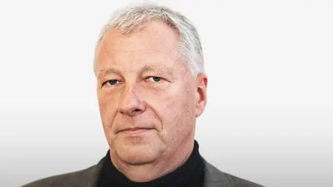 Porträt eines älteren Mannes mit grauen Haaren.