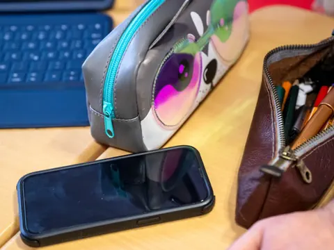 Smartphone und zwei Federmäppchen auf einem Tisch.