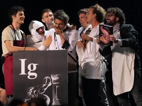 Eine Gruppe von Männern steht an einem Podium mit Mikrofonen und lacht.