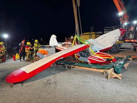 Zerstörtes kleines Flugzeug mit Feuerwehrleuten bei Nacht.
