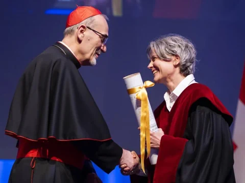 Pizzaballa und Hoffmann schütteln sich die Hand auf einer Bühne, sie hält eine gerollte Urkunde in der anderen Hand.