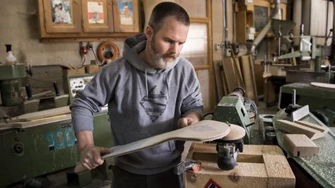 Mann arbeitet mit Holz in einer Werkstatt.