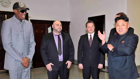 Gruppe von Männern in Anzügen in einem Raum, einer klatscht.