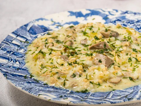 Teller mit cremigem Risotto, garniert mit Kräutern und Pilzen.