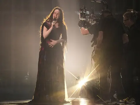 Eine junge Frau singt auf der Bühne und wird dabei gefilmt