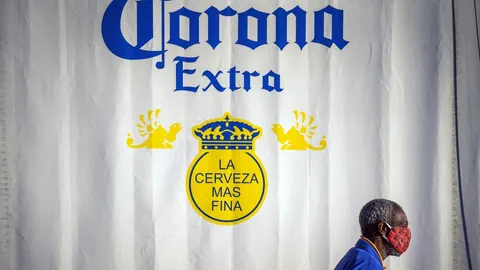 Ein Mann mit einer Maske vor einer Corona-Bierwerbung