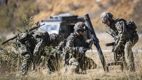 Drei Soldaten in Tarnkleidung mit Mörser im Gelände.