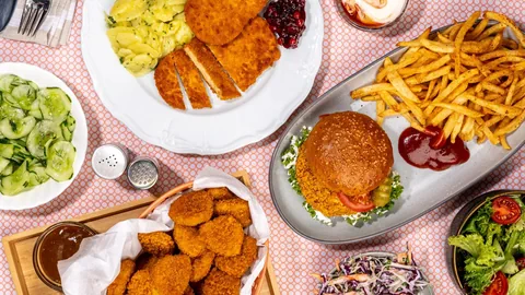 Verschiedene Teller mit Pommes, Salaten und Planted-Produkten.