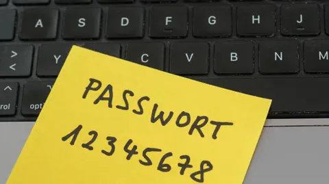 Ein gelber Notizzettel mit der Aufschrift «Passwort 12345678» liegt auf einem Laptop-Keyboard.