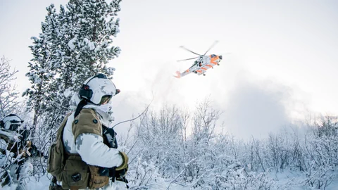  Soldaten betrachten einen abfliegenden Helikopter.