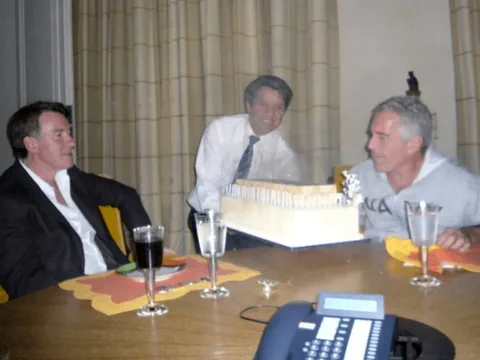 Drei Männer am Tisch mit einer Torte und Getränken.