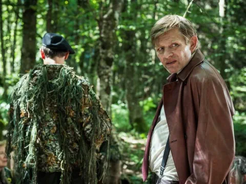 Mann im braunen Mantel im Wald.