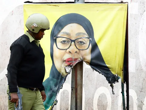 Polizist geht an zerrissenem Wahlplakat vorbei.