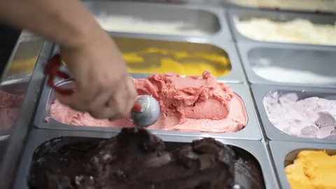 Hand schöpft Eis aus Eisbehälter.
