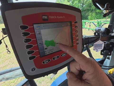 Finger tippt auf landwirtschaftliches GPS-Gerät in Traktor.