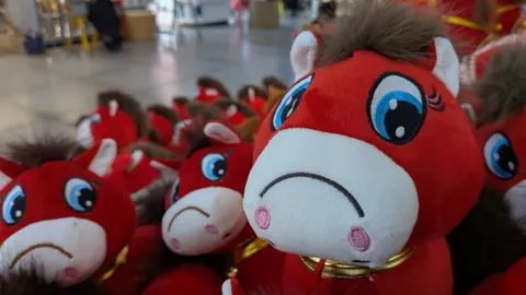 Gruppe von roten Plüschpferden mit traurigem Gesichtsausdruck.