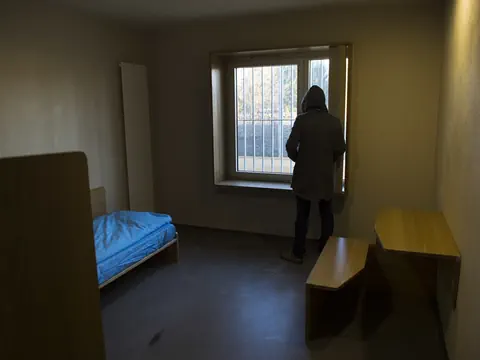 Person steht in einer Zelle und schaut aus dem Fenster.