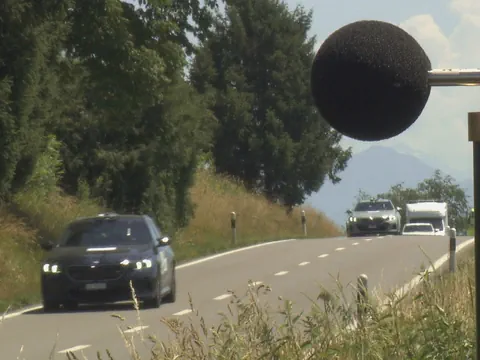 Autos auf einer Landstrasse mit Mikrofon im Vordergrund.