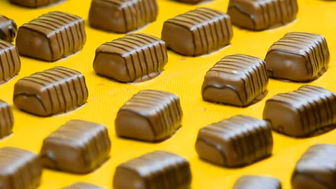 Reihen von Pralinen auf gelber Oberfläche.